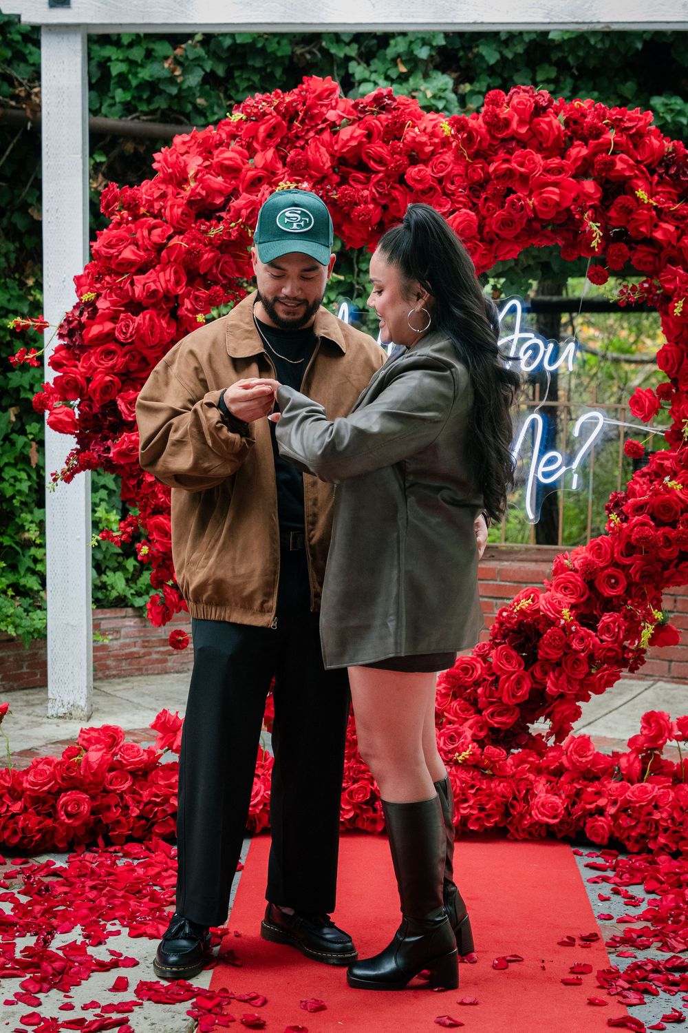 Couples share intimate moments under a pergola decorated with red flowers and neon signage.