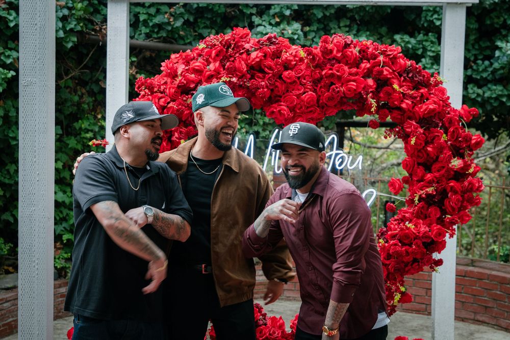 Guests celebrate under a white pergola adorned with dramatic red floral installations.