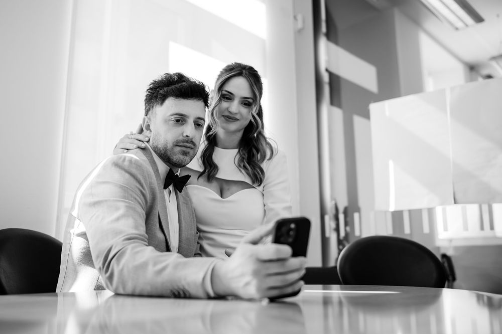 Two people sitting at a table looking at a smartphone together in black and white photography.