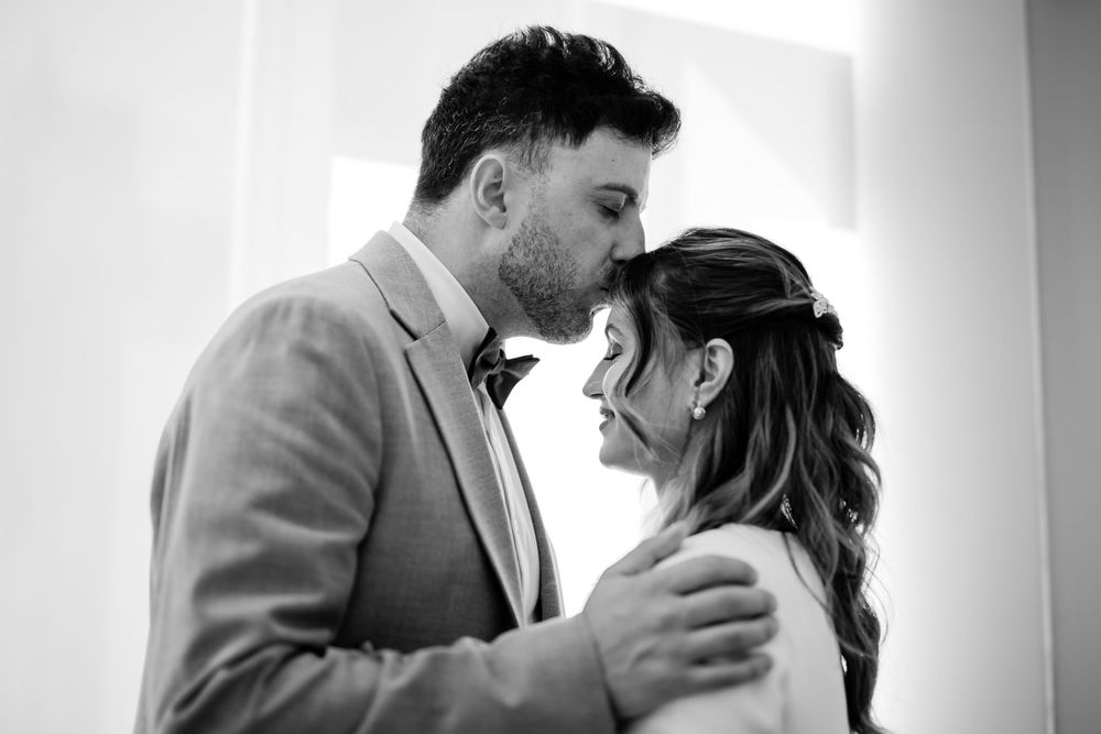 Four black and white romantic wedding photos show tender moments between a bride and groom during their ceremony.