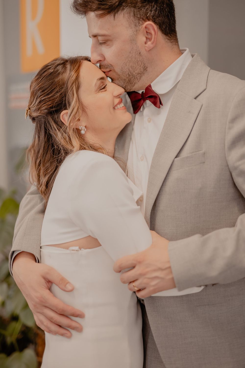 A romantic wedding couple shares an intimate moment in a light gray suit and white dress.