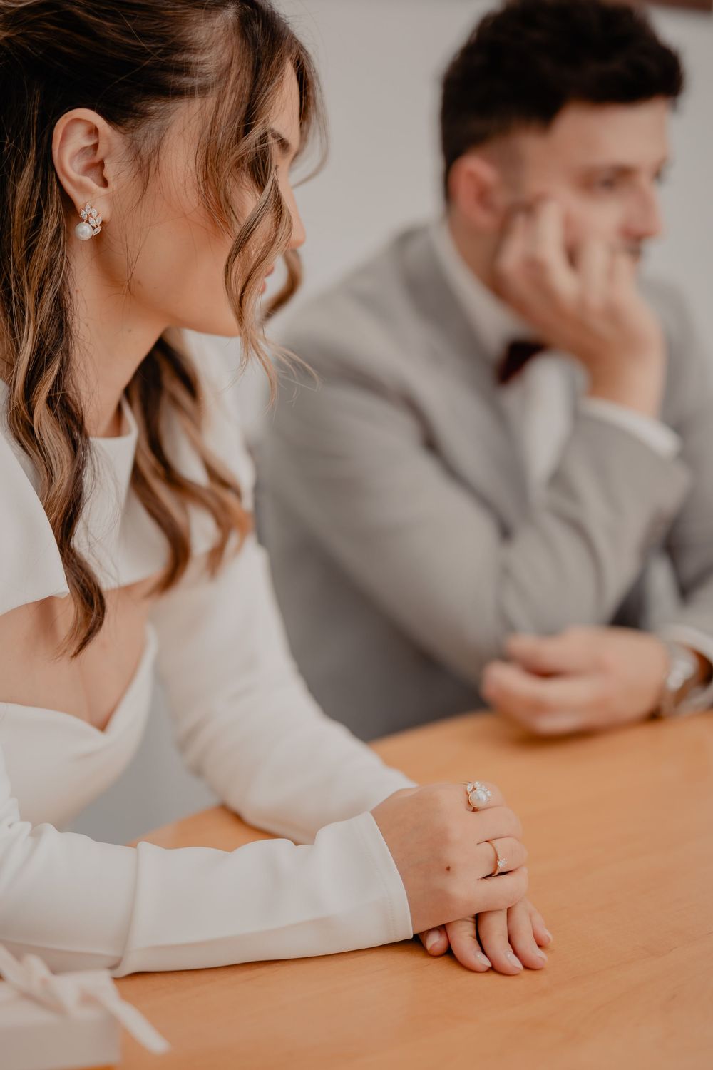 A couple sits at a wooden table during what appears to be a serious discussion or meeting.