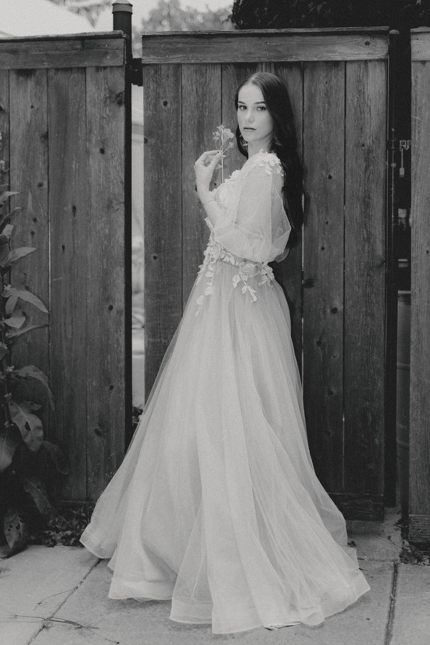 A series of black and white photos showing a flowing white wedding dress against a rustic wooden fence backdrop.