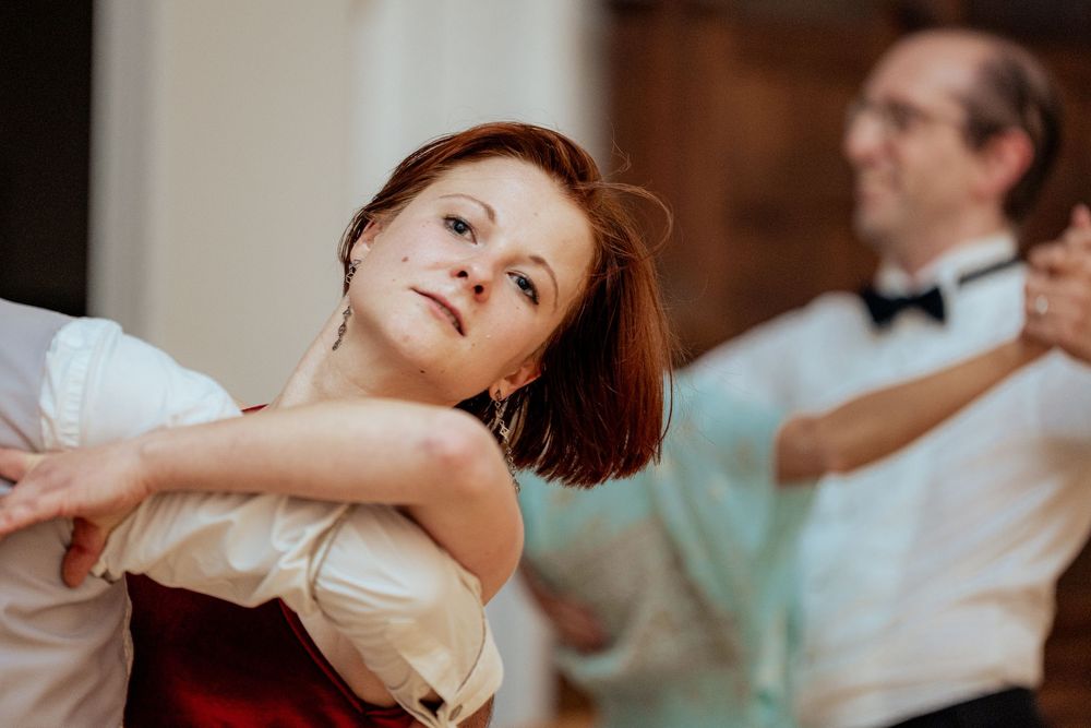 Dancers in elegant attire perform graceful movements during a ballroom dance competition.