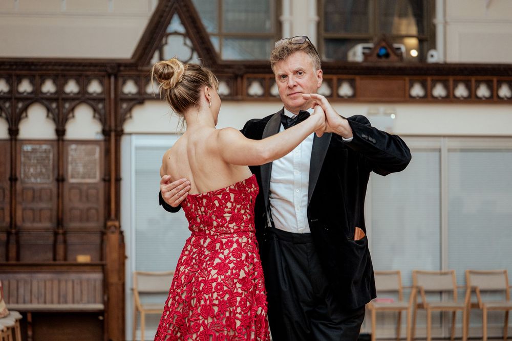 Couple dancing together in an elegant venue with ornate wooden decor.