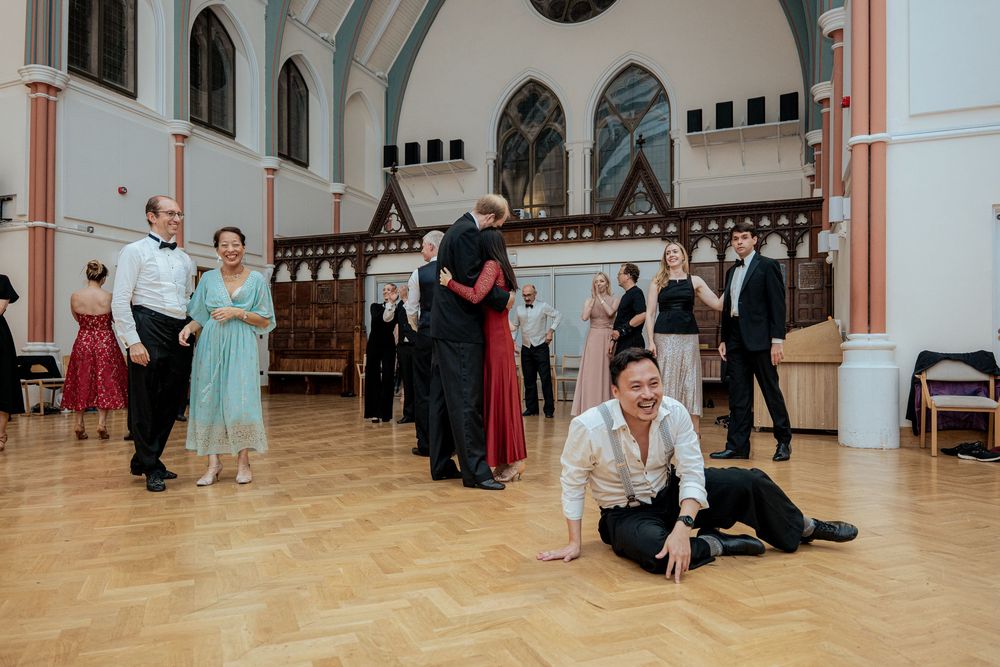 Ballroom dance class in progress with multiple couples practicing in a bright studio space.