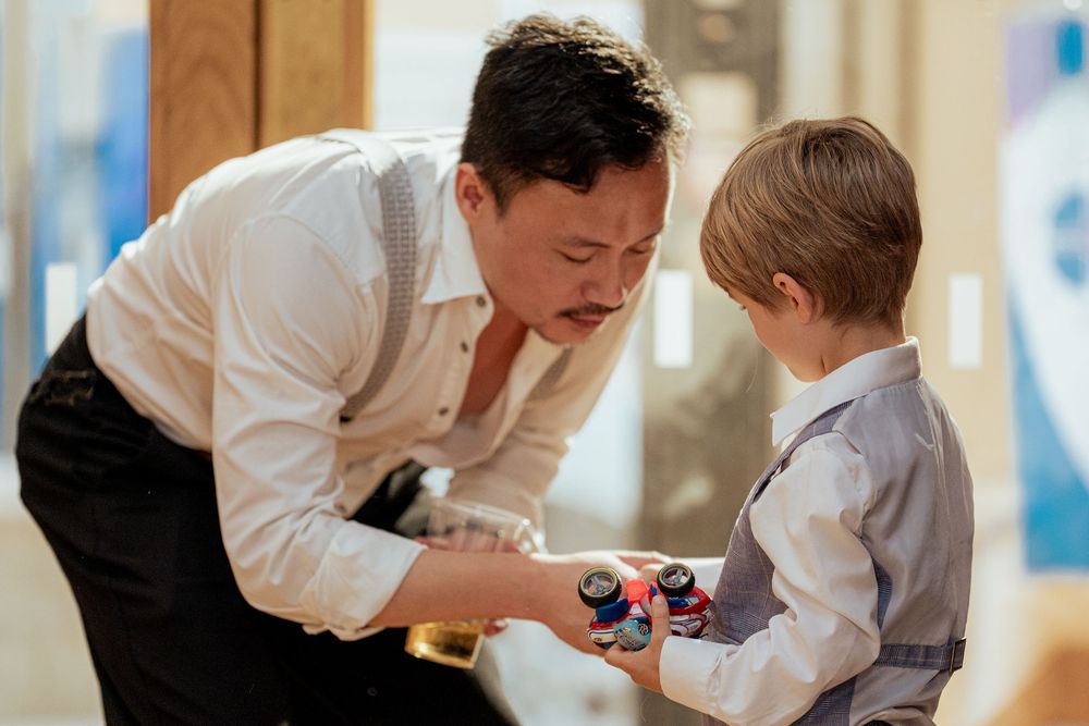 A young boy receiving a gift or present from an adult in a casual indoor setting.