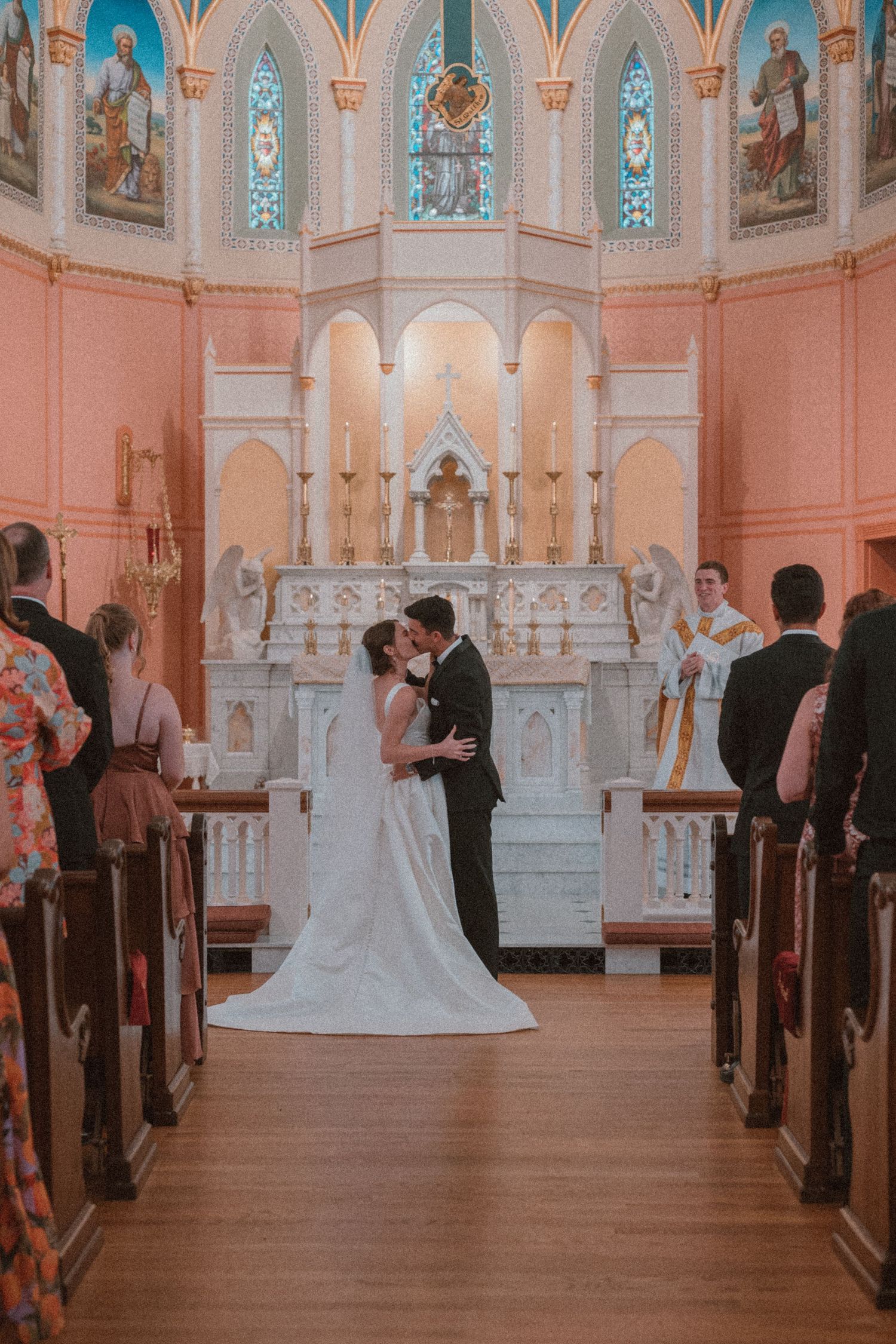 Bride and groom exchanging vows and first kiss at St. Francis of Assisi Church, Staunton, VA, emotional, documentary-style wedding photo.