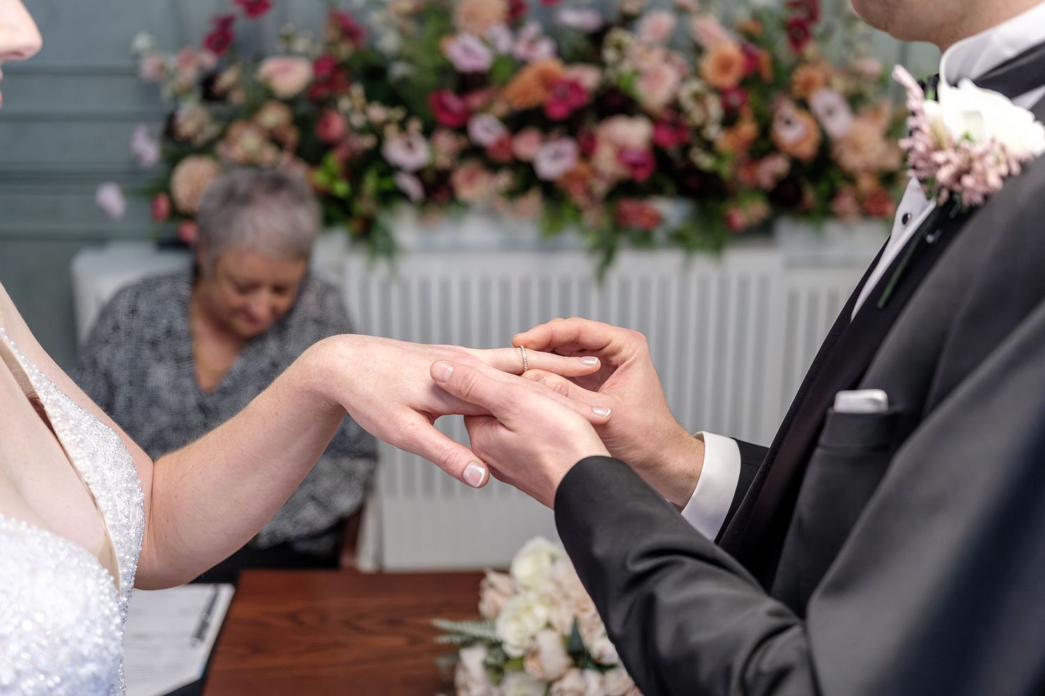 Wedding ceremony moment showing couple exchanging rings at an indoor venue with classic decor.