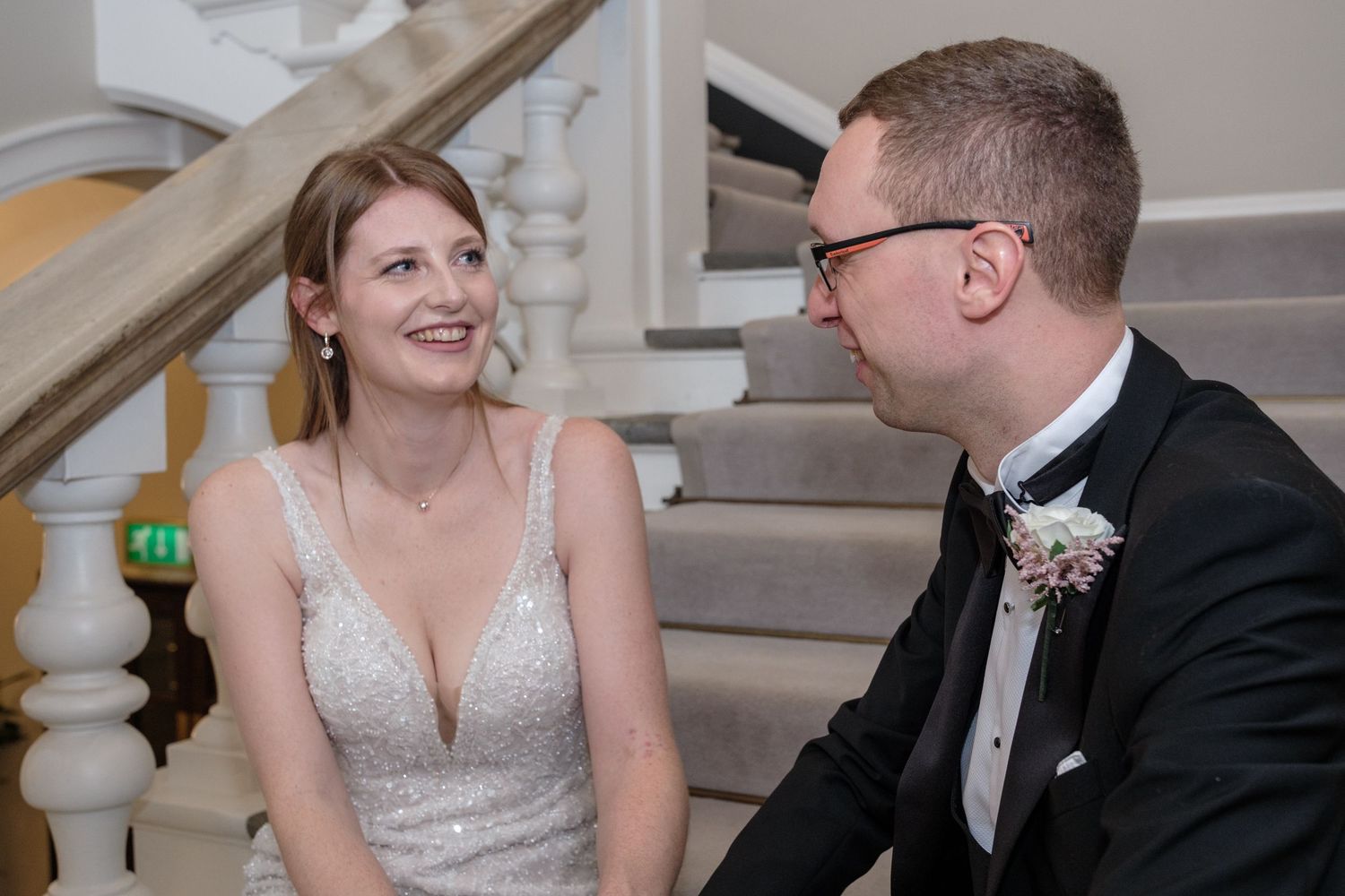 A couple shares a joyful moment together during their wedding reception in a grand venue with white columns.