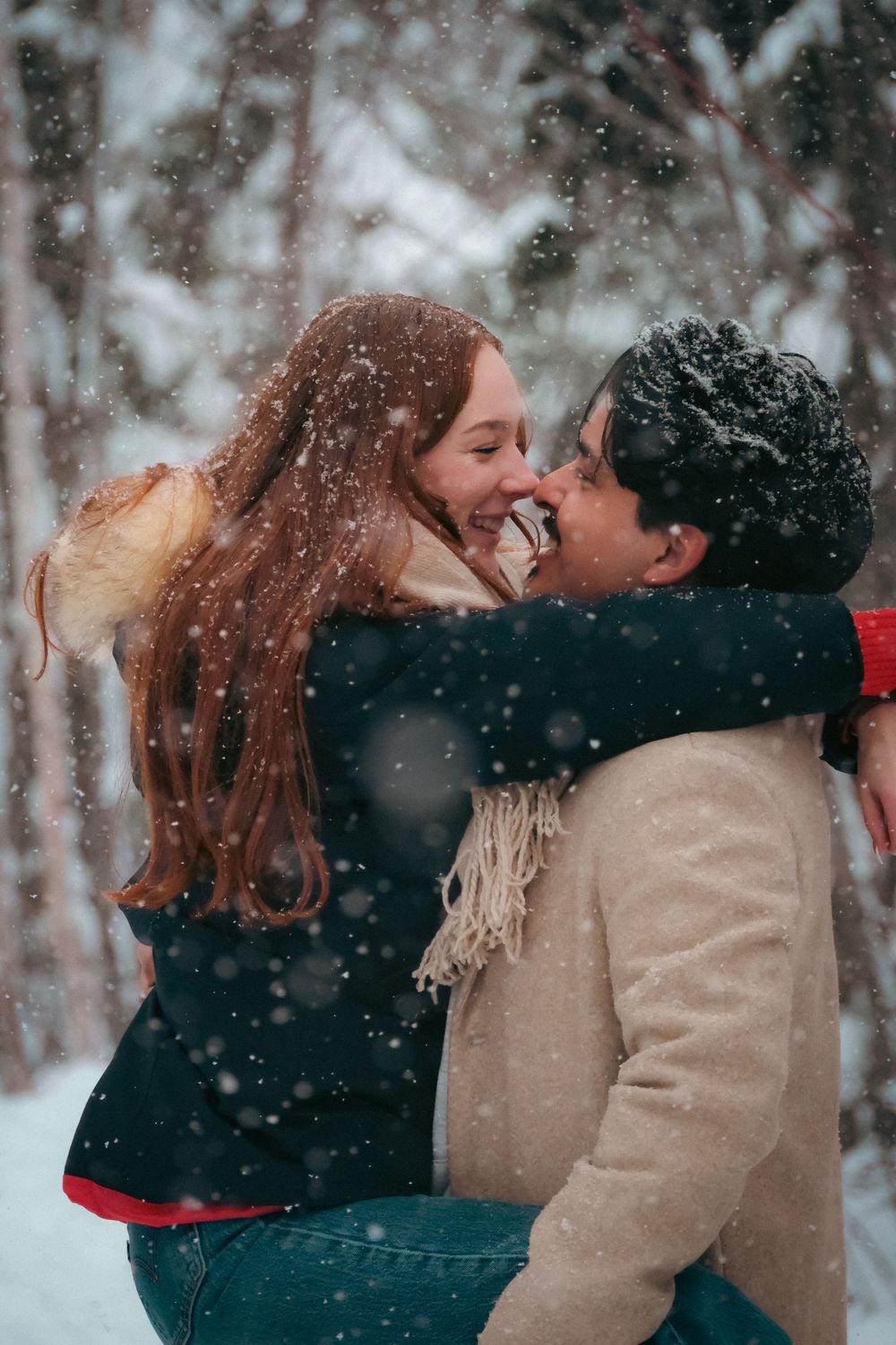 Romantic winter scene with falling snow and warm embraces in a forest setting.