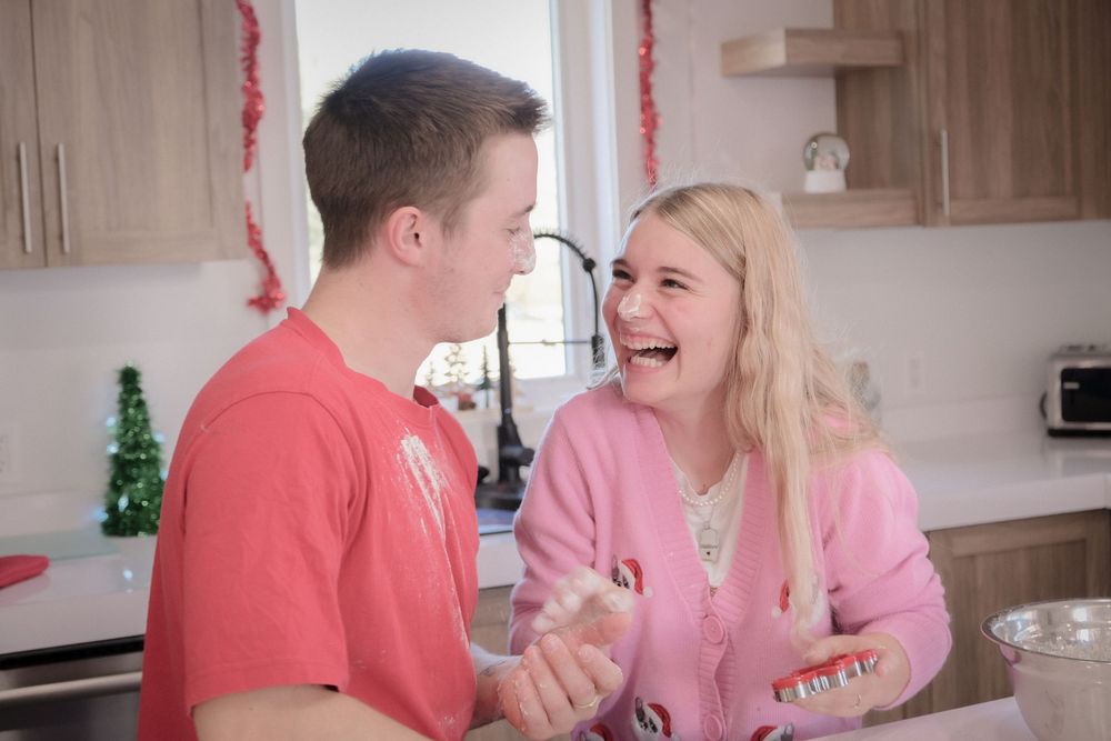 Couple in matching coral and pink outfits sharing a playful moment in a kitchen setting.
