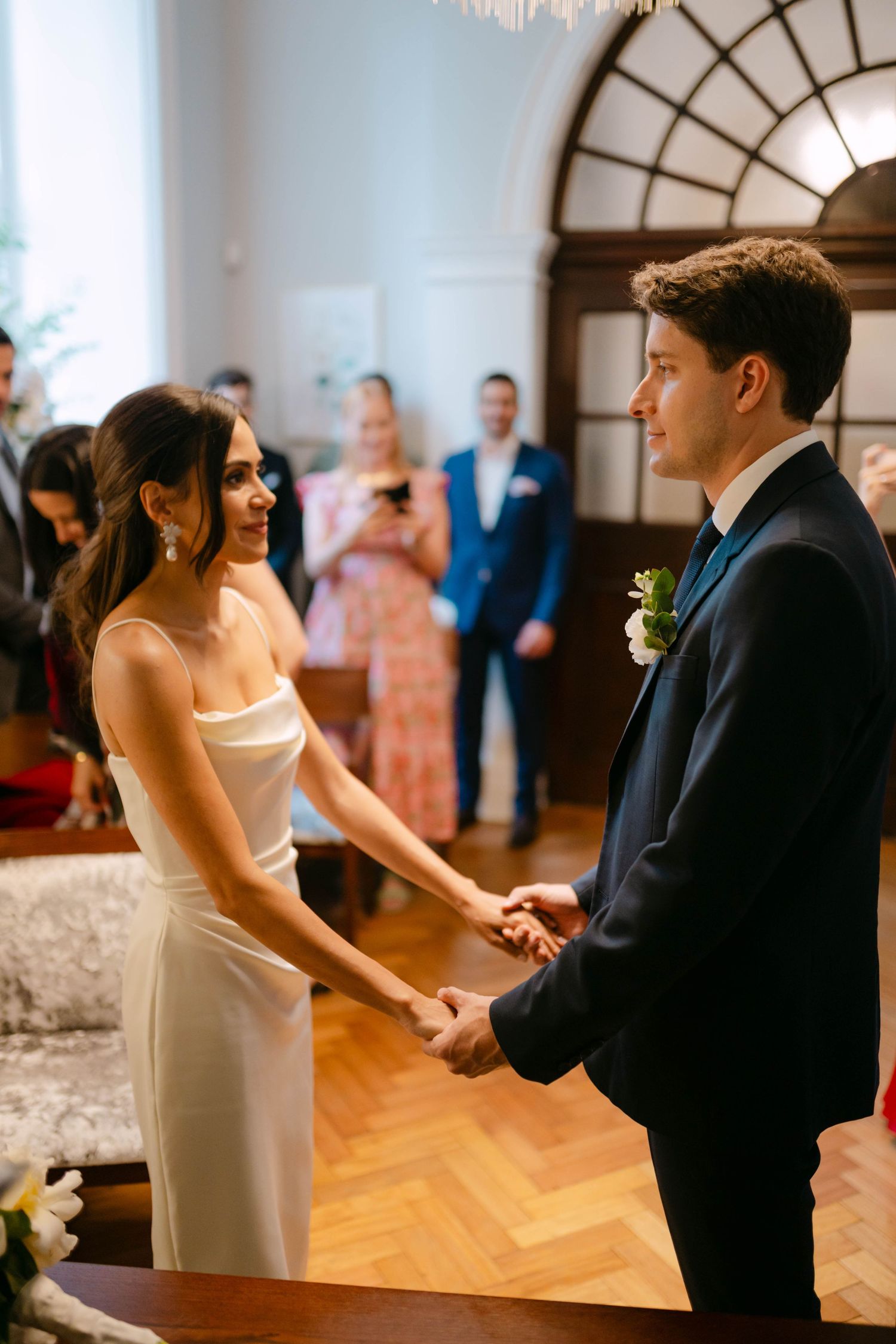 Couple dancing in elegant venue with arched windows and hardwood floors.