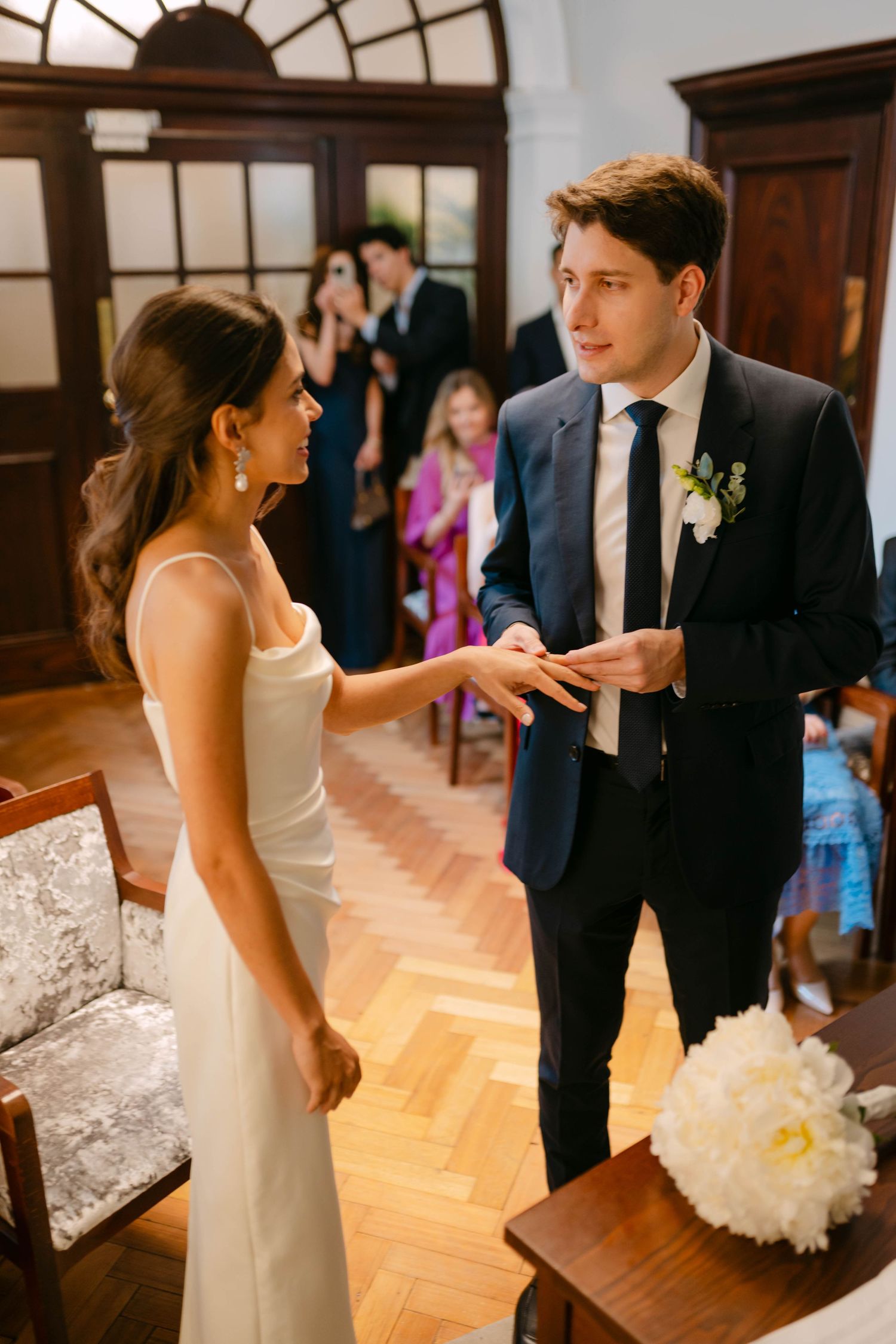 Wedding celebration in elegant room with hardwood floors and arched windows.