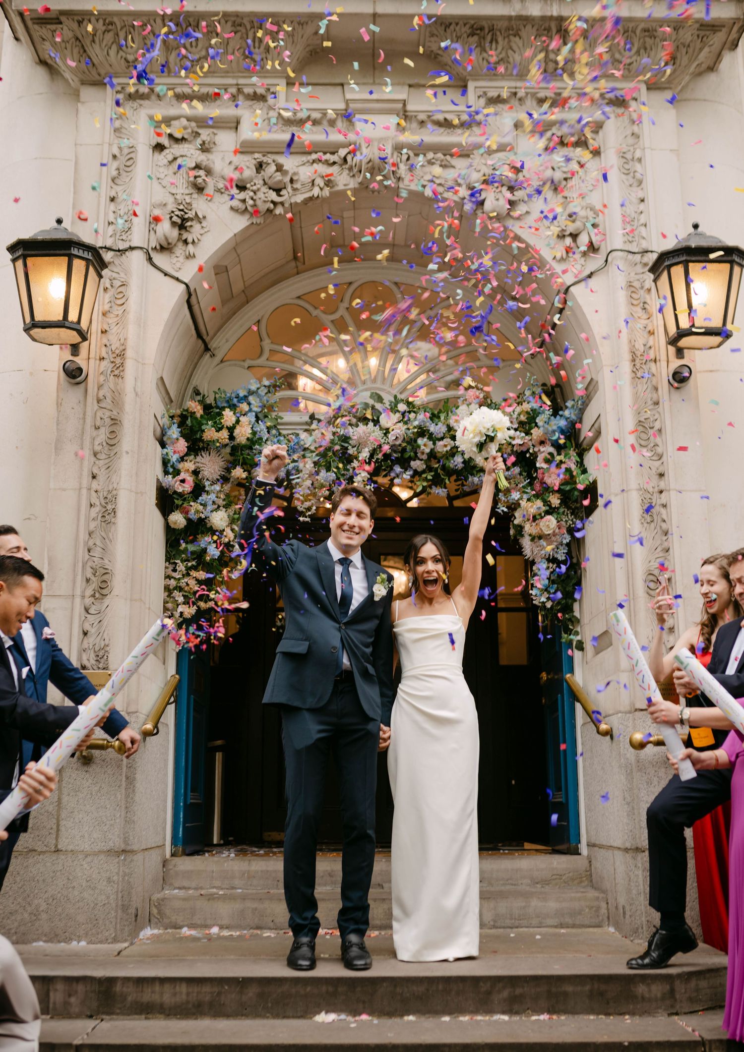 Celebratory moment with confetti being thrown under an ornate archway entrance.