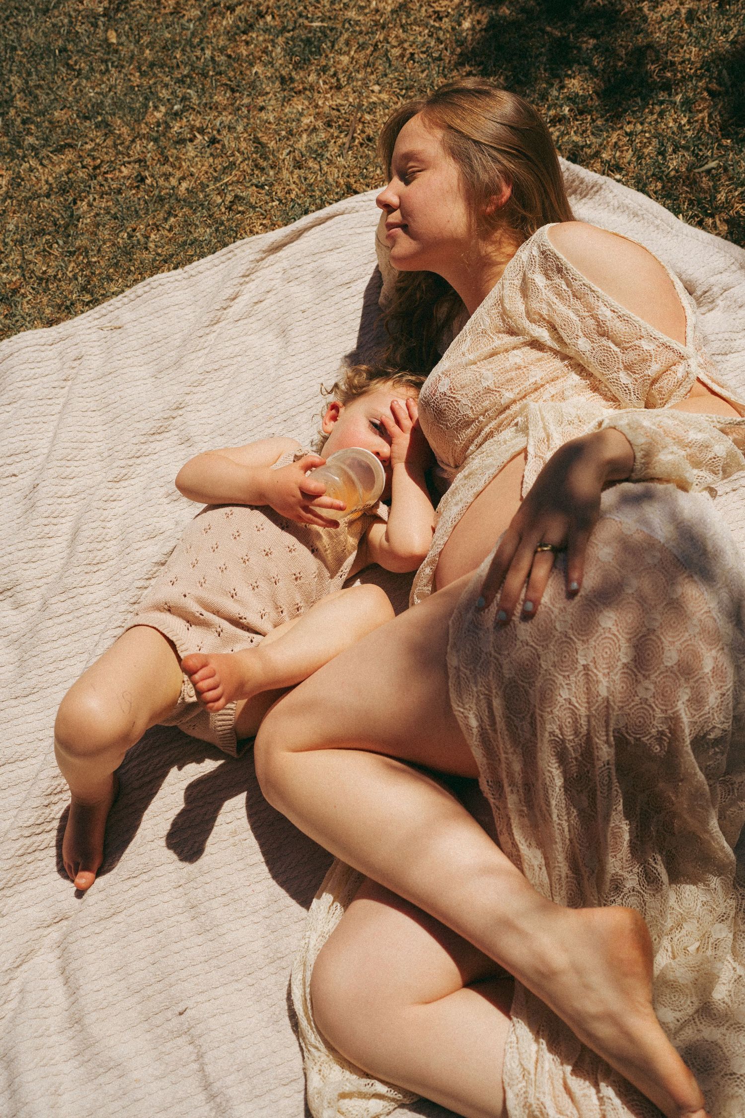 Intimate outdoor portrait of two people resting together on white fabric.