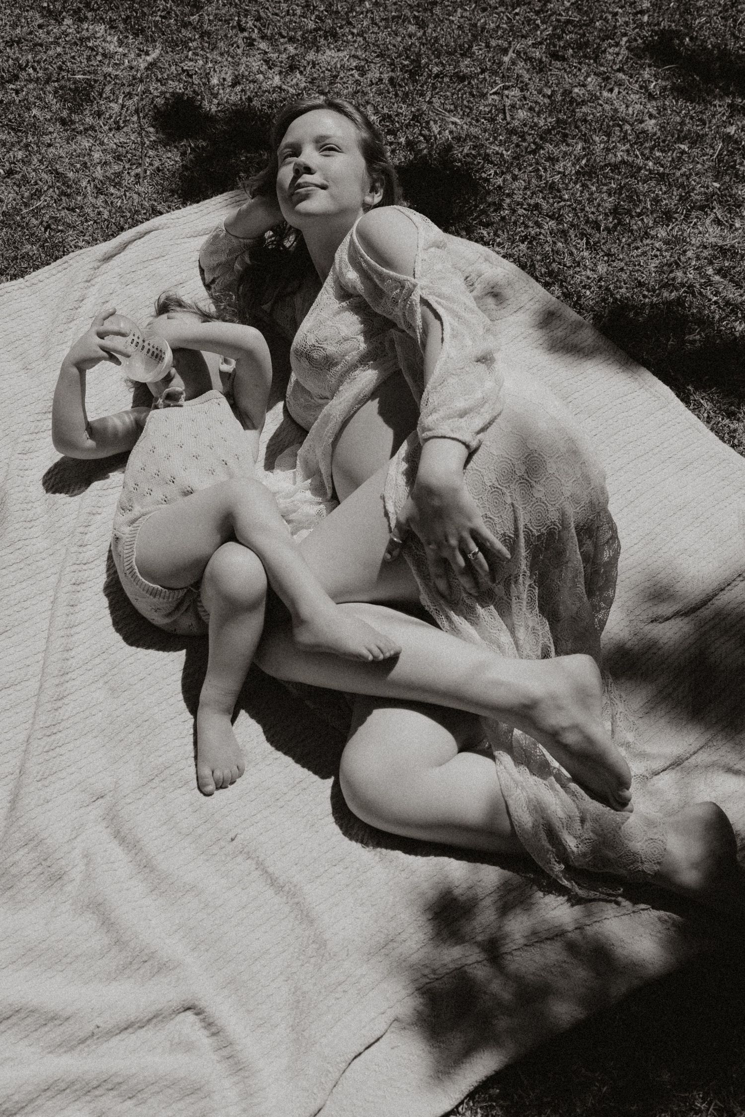 Black and white photo of figures relaxing on a blanket outdoors.