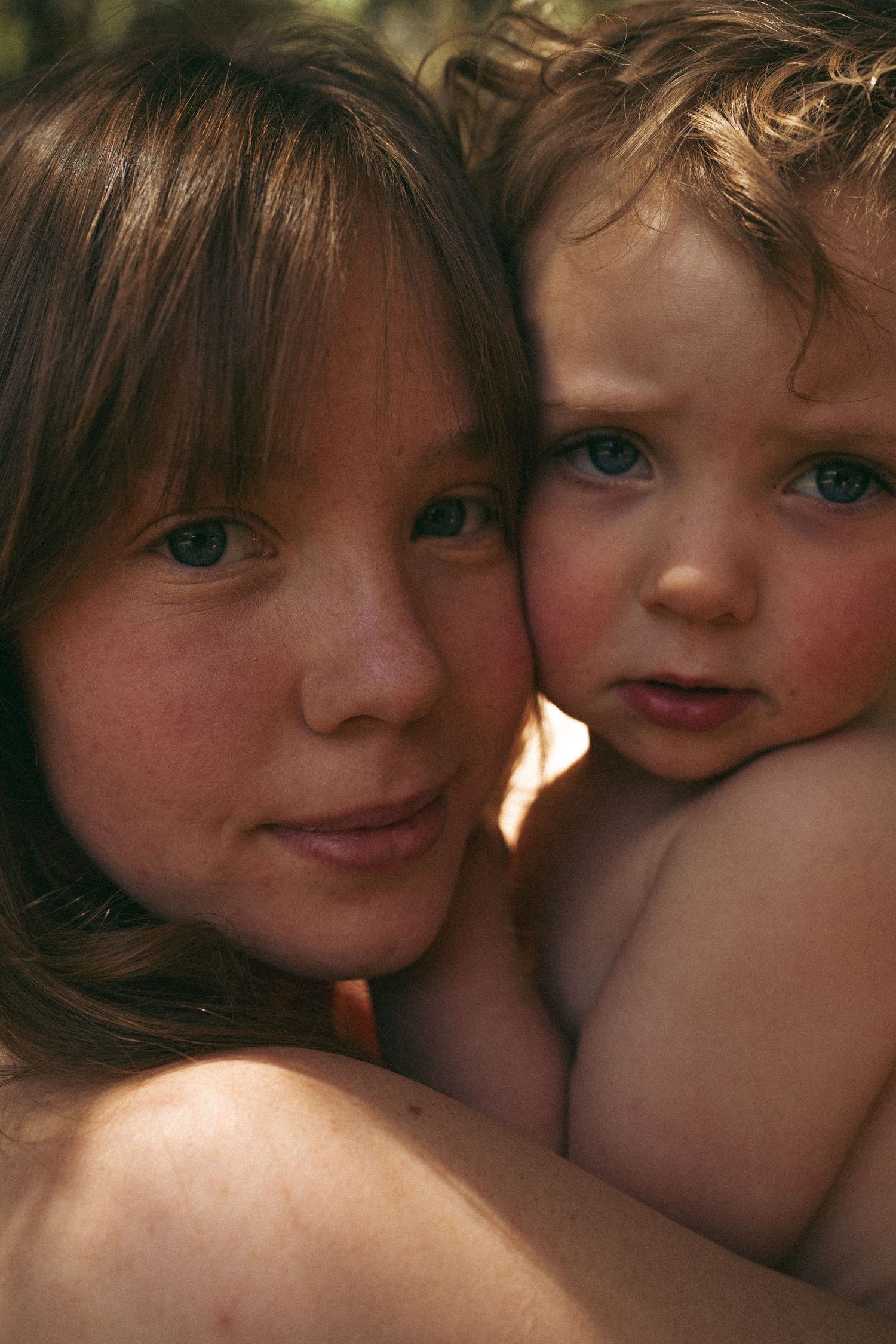 Intimate portrait of parent and child with striking blue eyes in warm lighting.