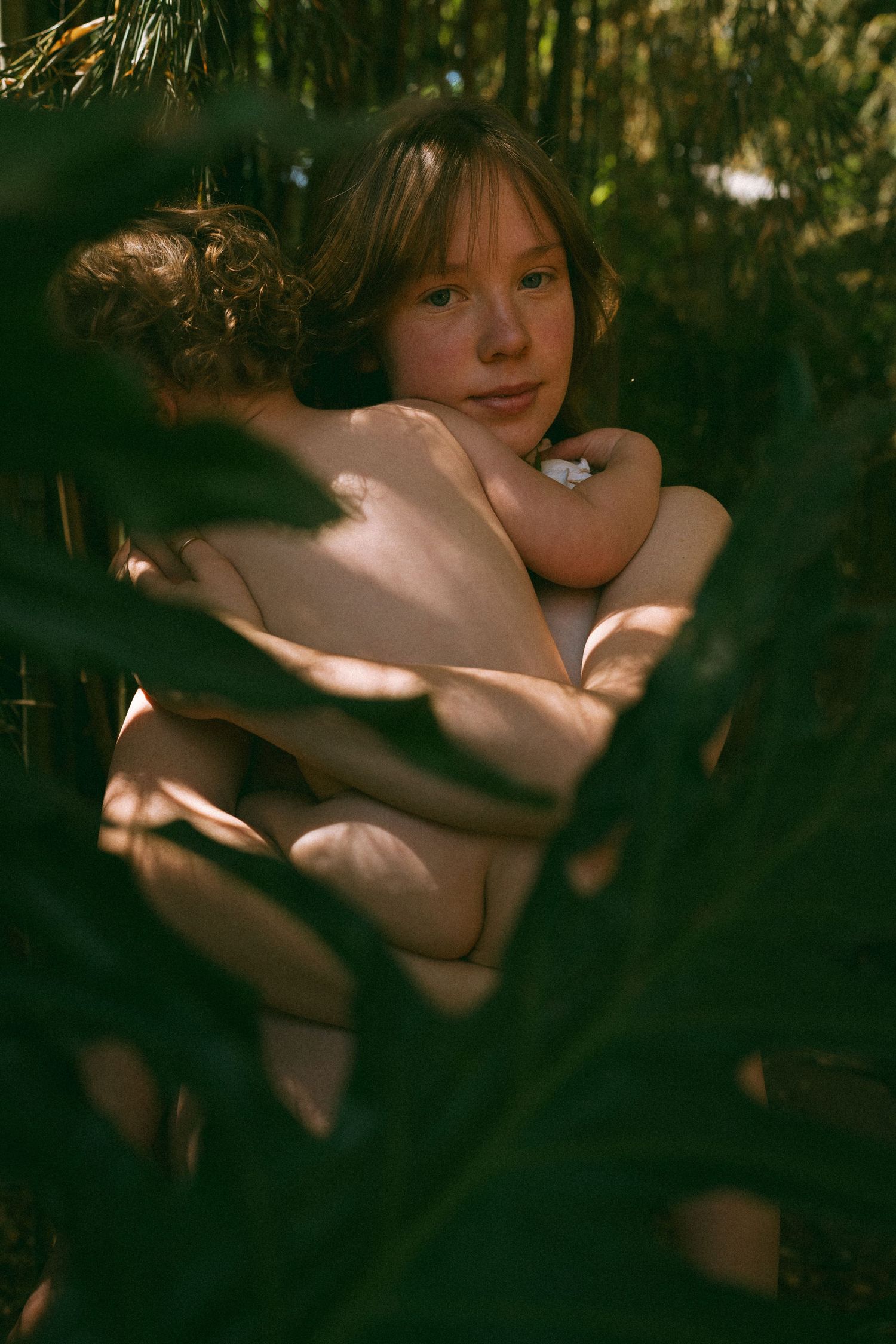 Portrait through tropical foliage showing peaceful expression in natural light.