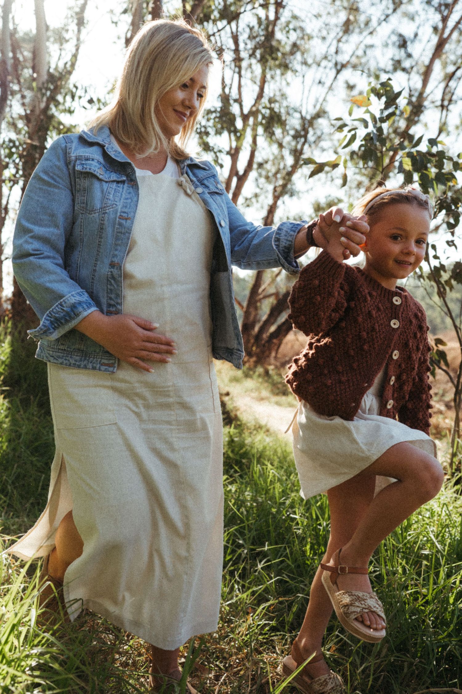 Playful moments captured in sunlit grassland with denim and white clothing.