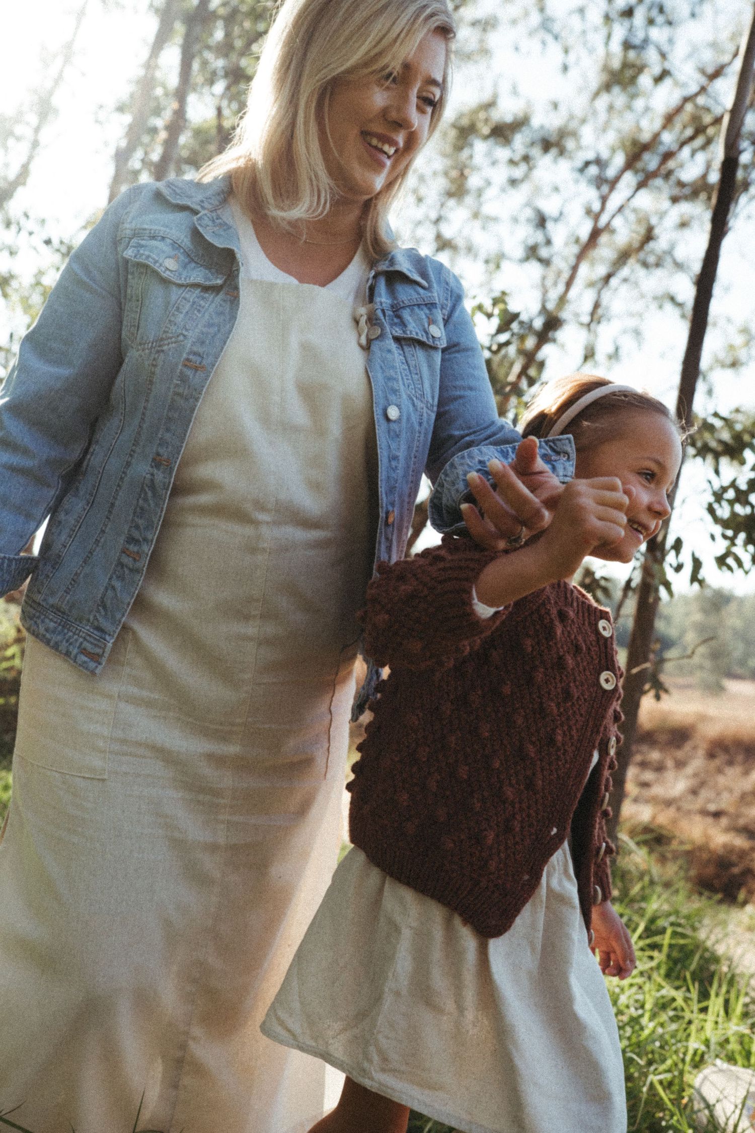 Two people share a tender moment outdoors while holding a brown knit item.