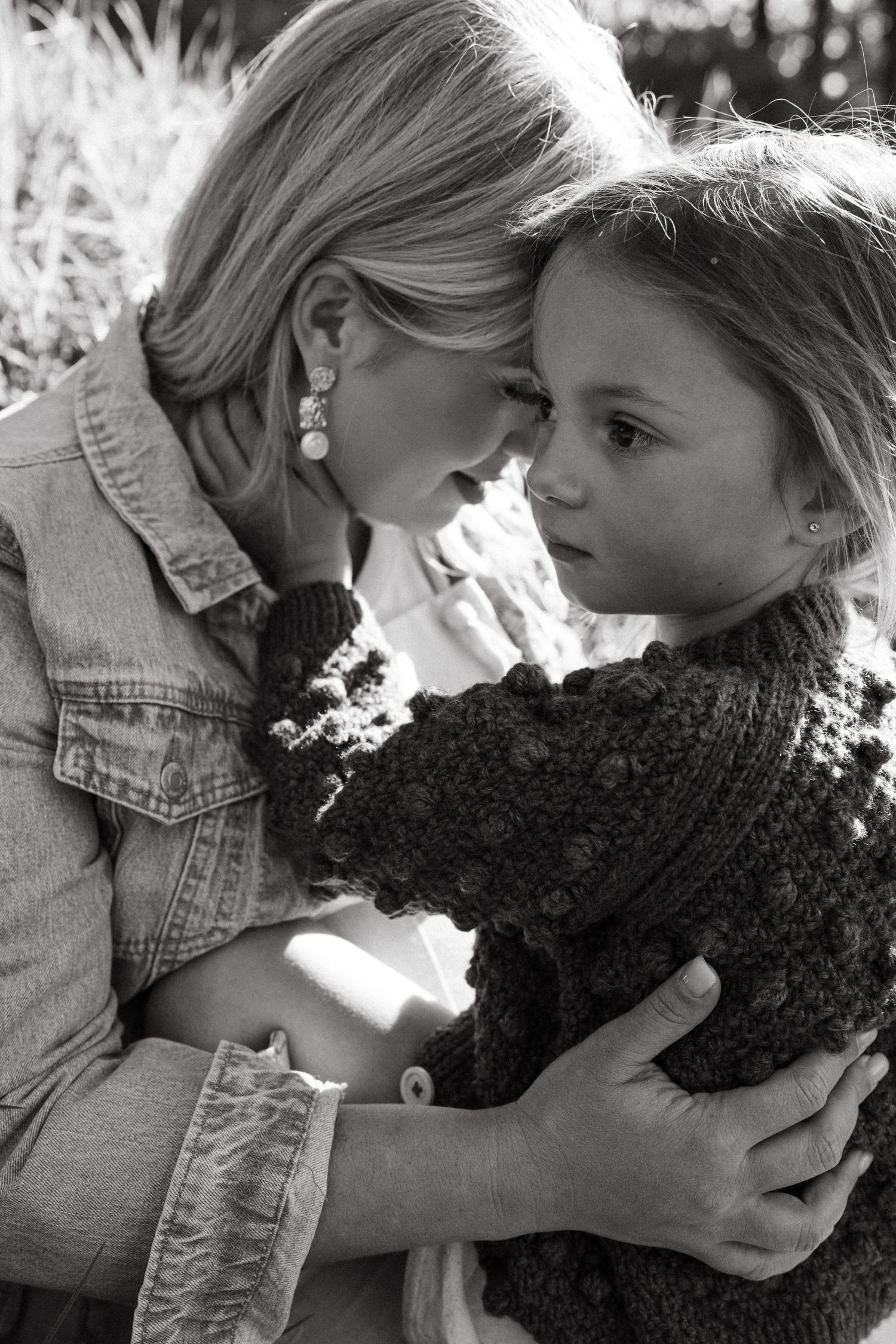 A black and white image captures an intimate moment between two people with a knit item.