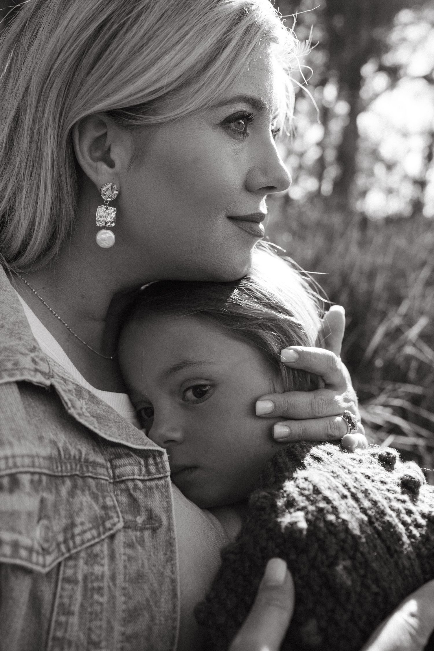 A black and white portrait showing elegant pearl drop earrings and denim jacket in profile.
