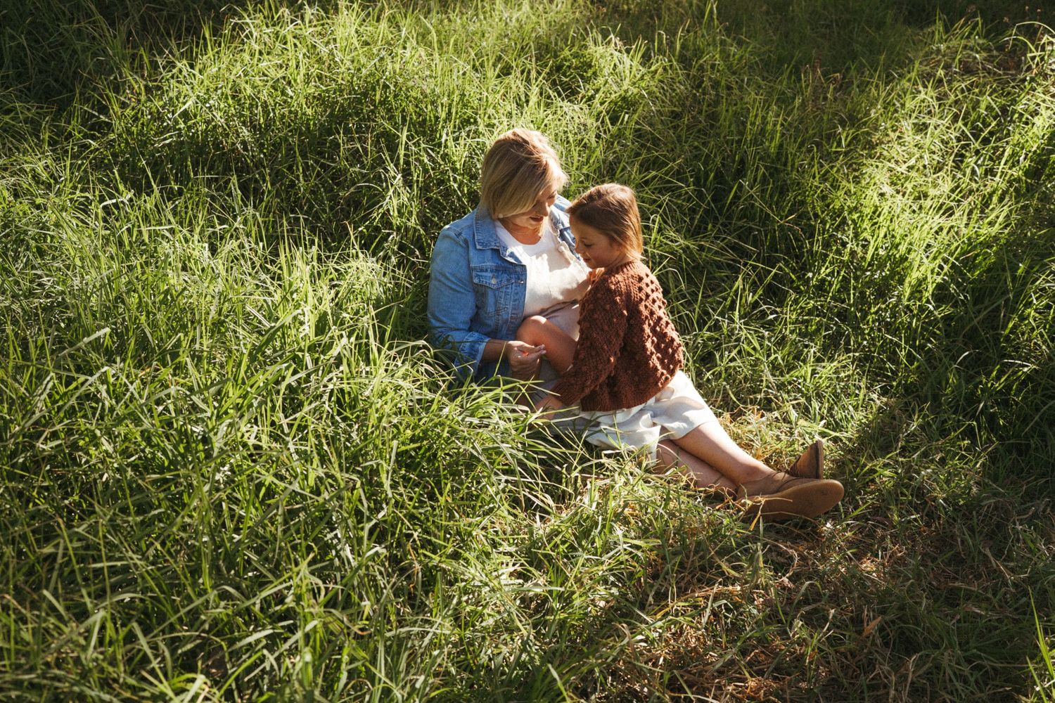 A peaceful outdoor scene with two people resting in tall grass on a sunny day.
