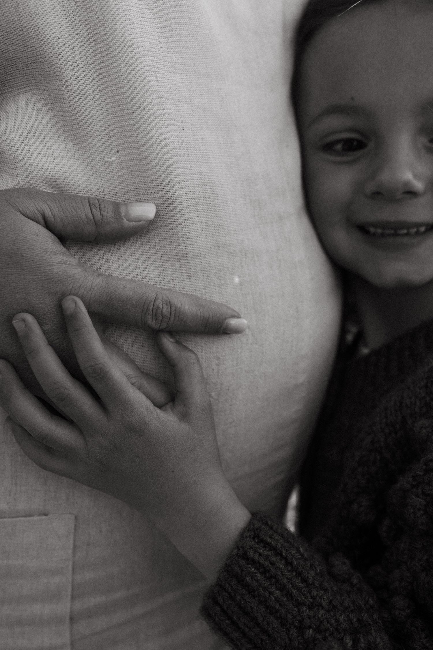 A close-up black and white image showing small hands against white fabric.
