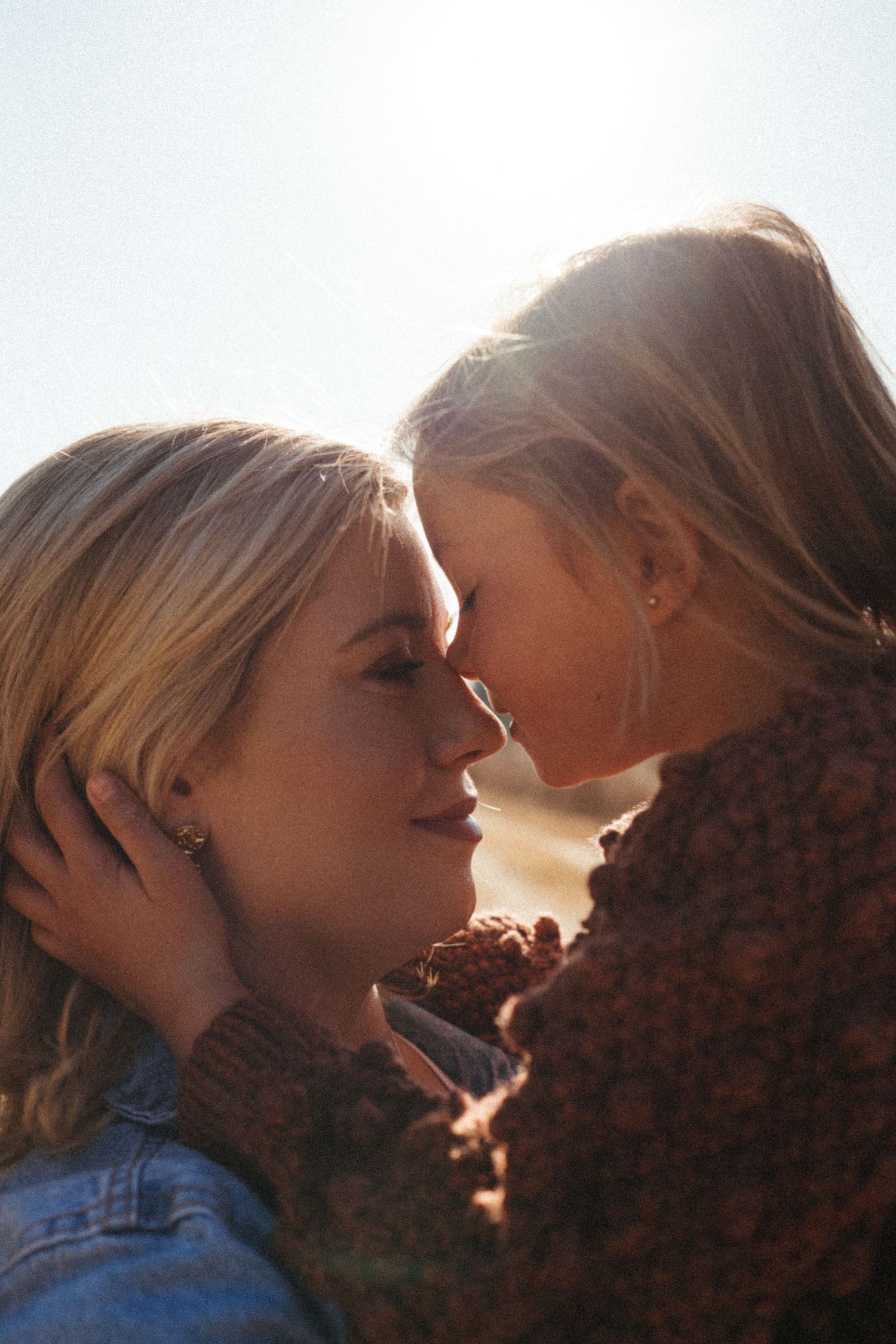 Intimate close-up portrait backlit by golden sunlight in natural setting.