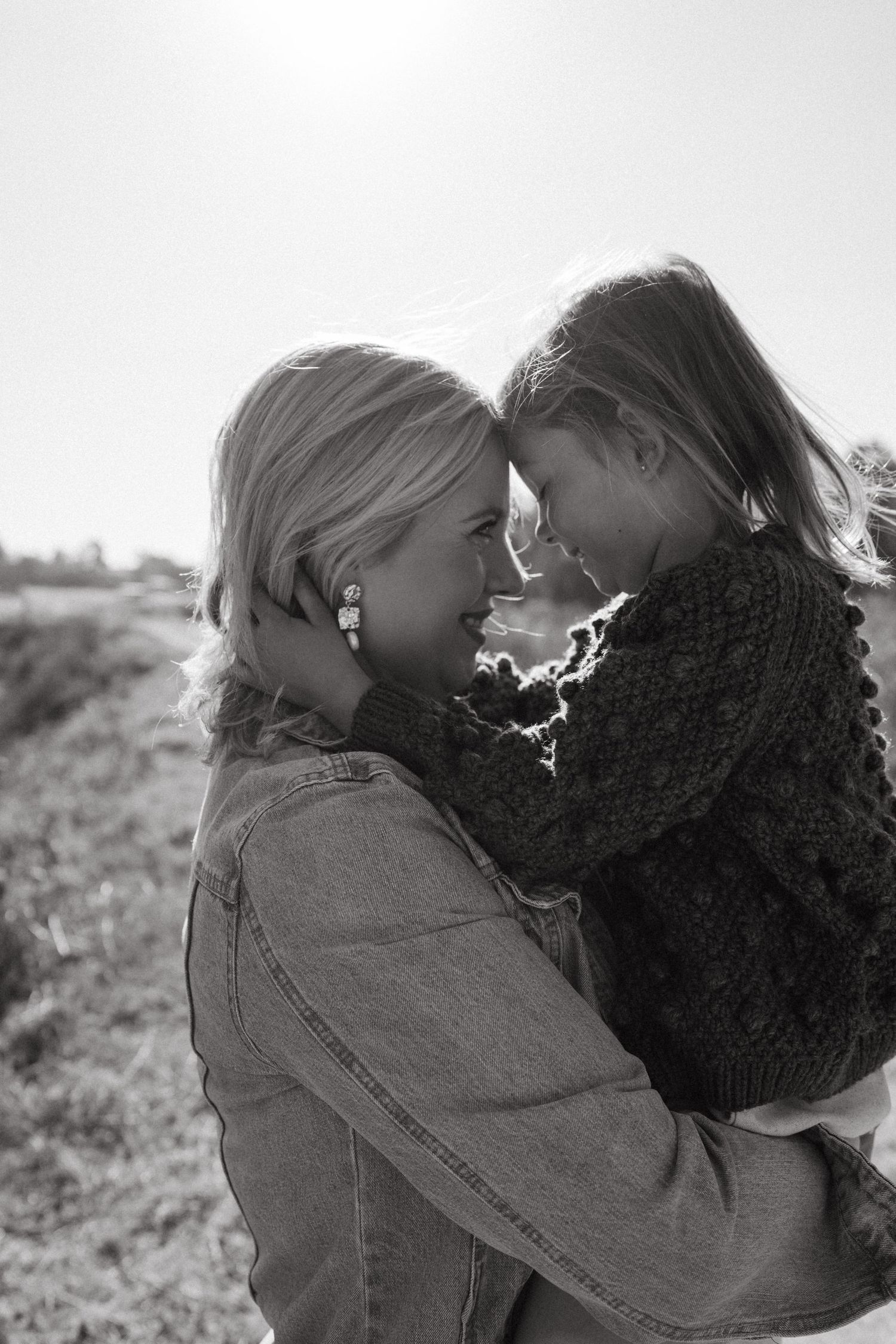 A tender moment captured in black and white showing an intimate embrace against a natural backdrop.