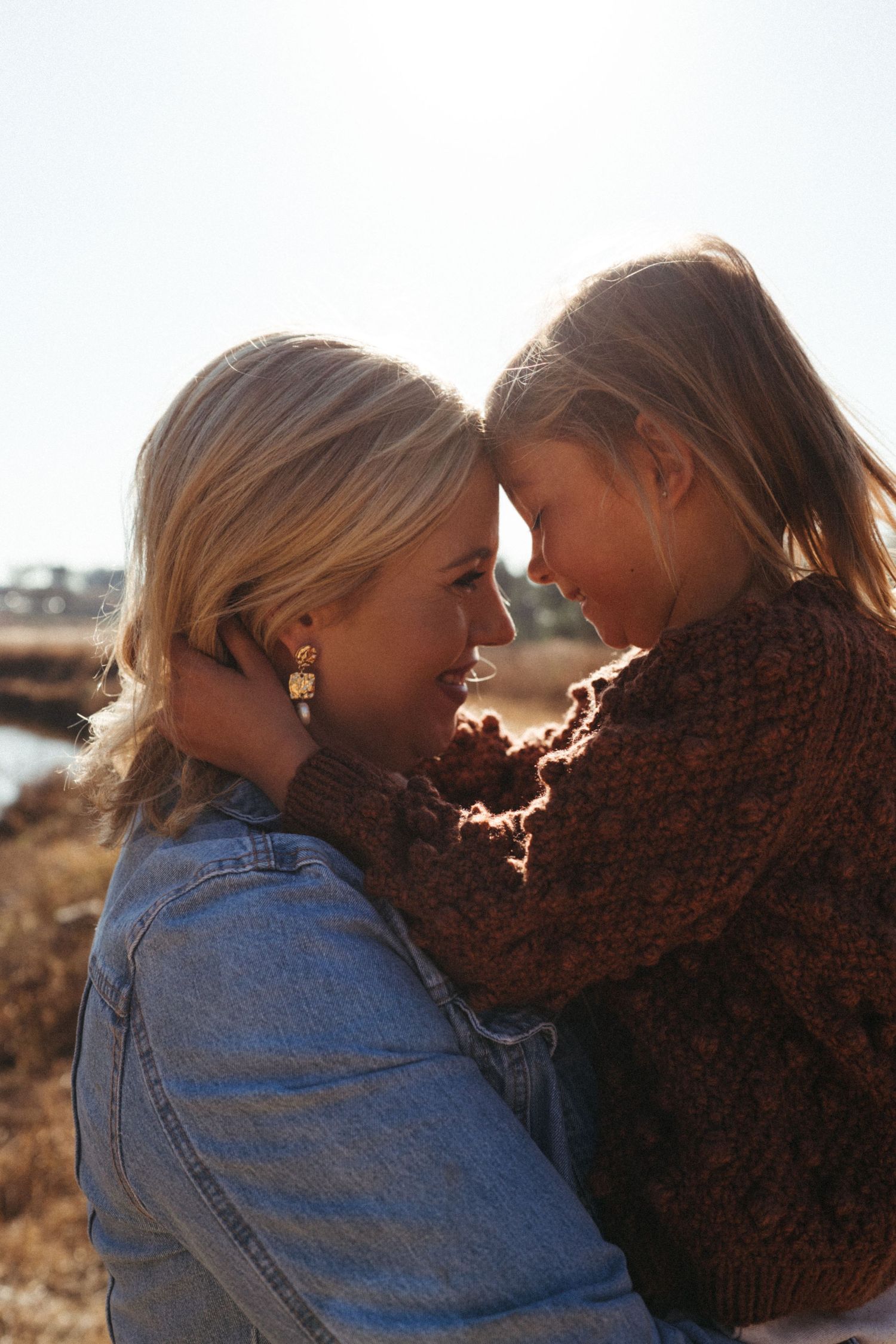 A romantic scene backlit by golden sunlight showing two people in a close embrace.