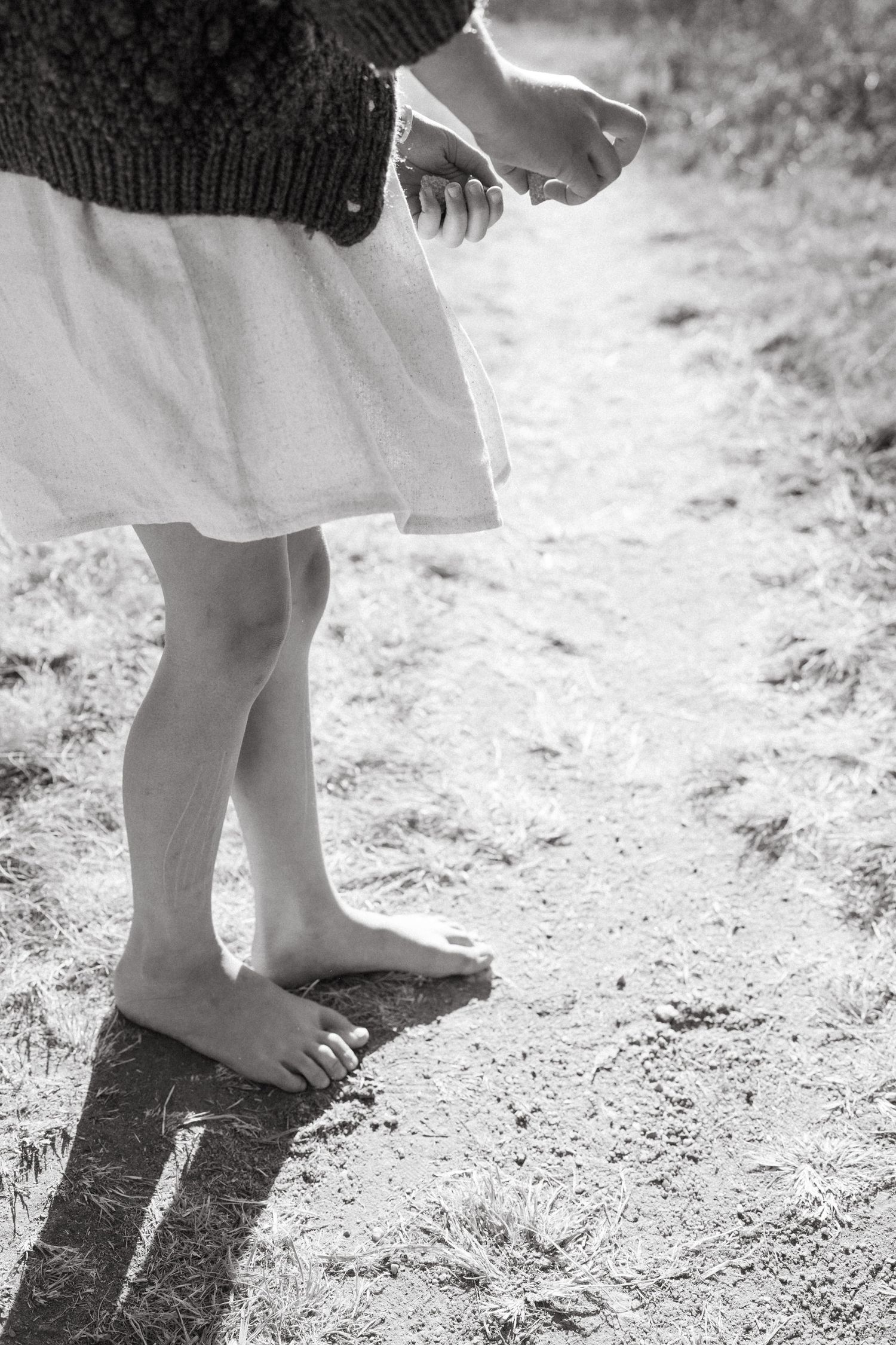 Black and white images of bare feet walking on a dusty ground creating shadows.