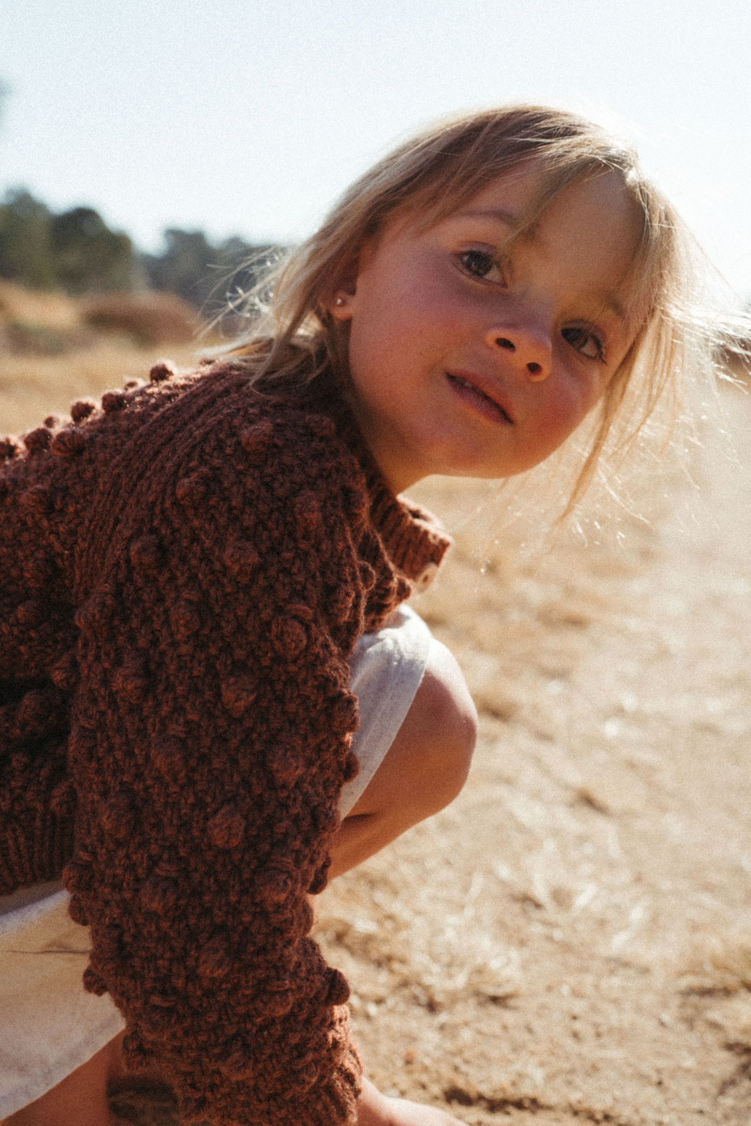 A series of artistic outdoor portraits showing a brown knit sweater against a sunlit background.