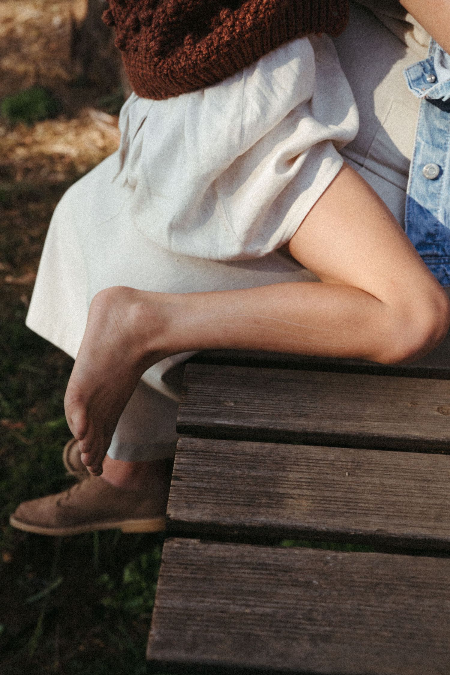 Close-up detail shots of hands resting on a wooden bench outdoors.
