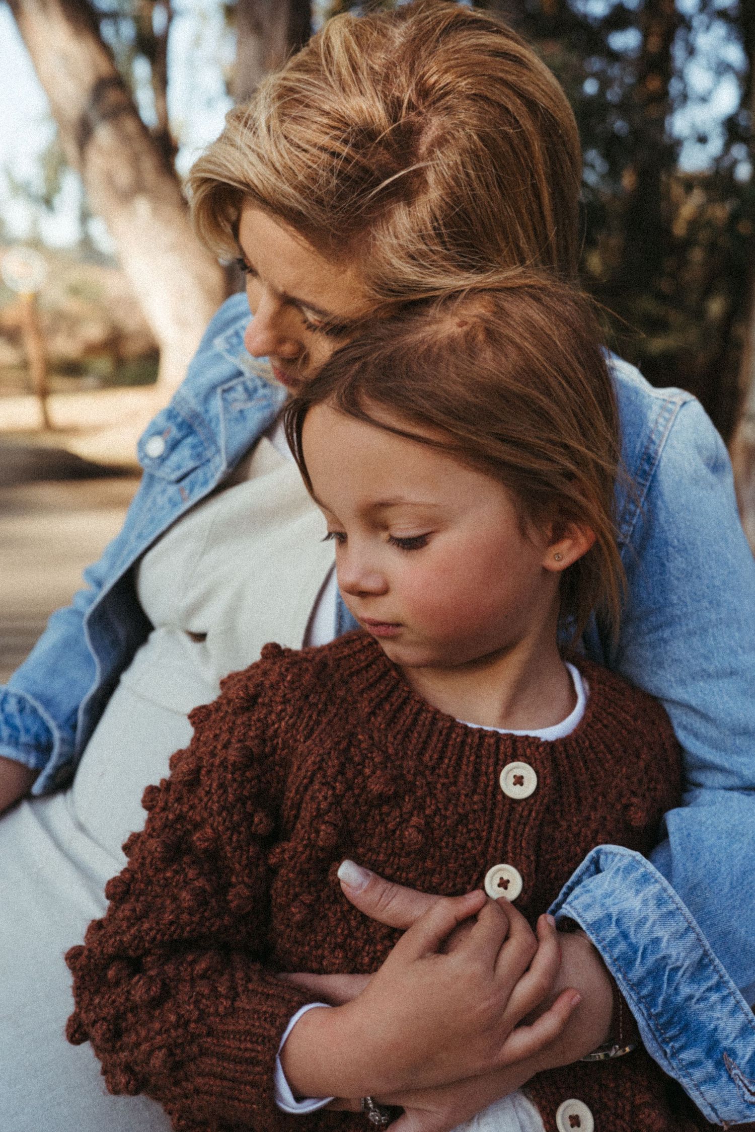Artistic series showing a chunky brown knit scarf with buttons in outdoor natural lighting.