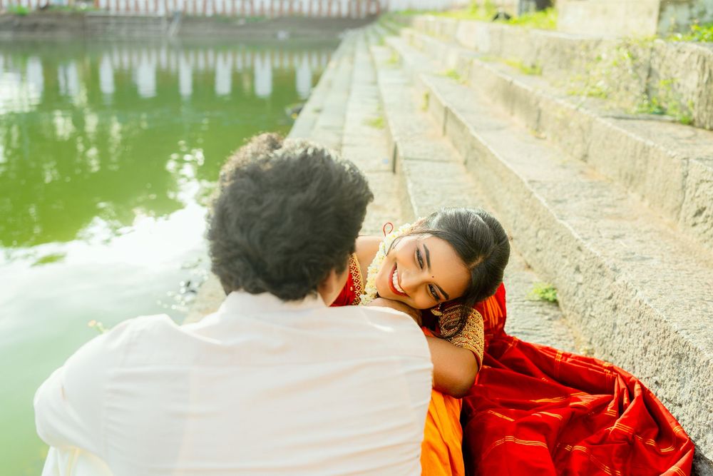 A romantic moment captured by a pond with traditional Indian clothing and architecture.