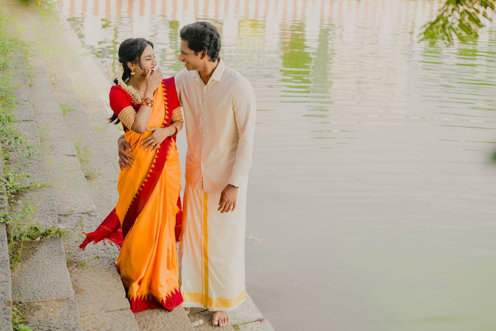 Couple in traditional Indian wedding attire share intimate moments by a serene lakeside.