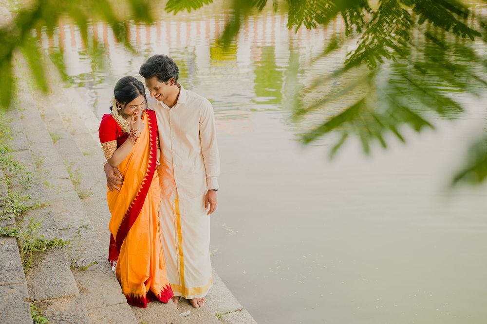 A couple in traditional Indian dress walks along a peaceful waterfront path.
