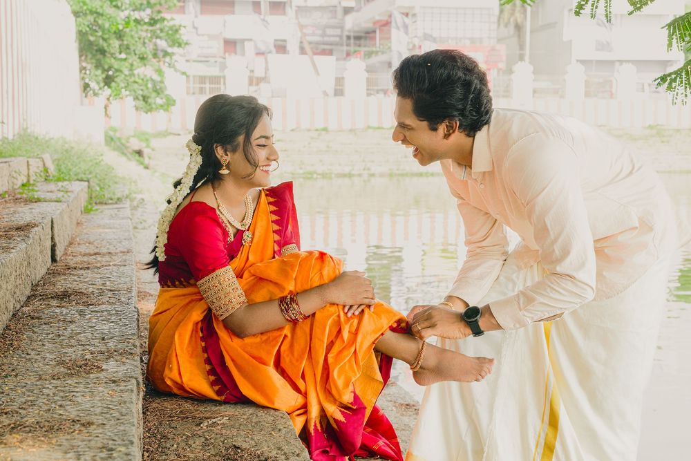 A couple shares a playful moment on stone steps while wearing traditional Indian clothing.