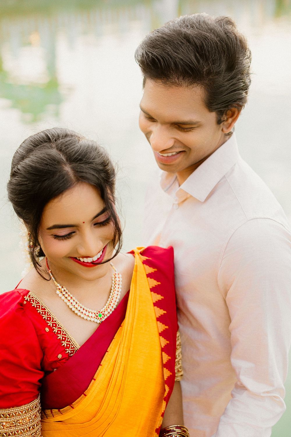 Romantic couple portrait in traditional Indian attire by the lake.