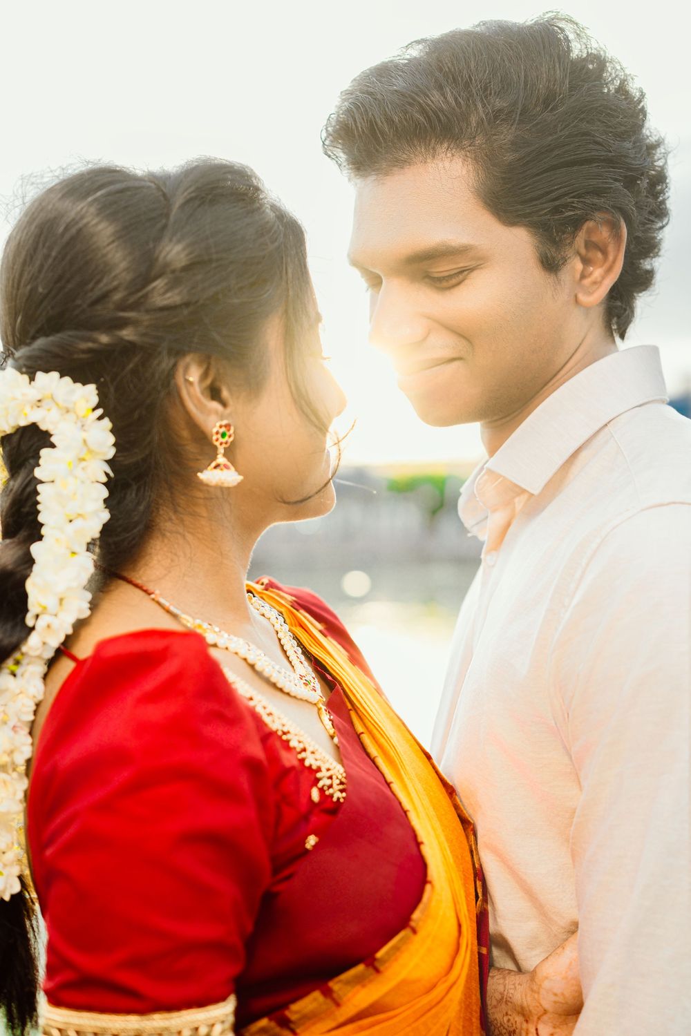 Intimate portrait of couple in traditional Indian wedding attire during golden hour.
