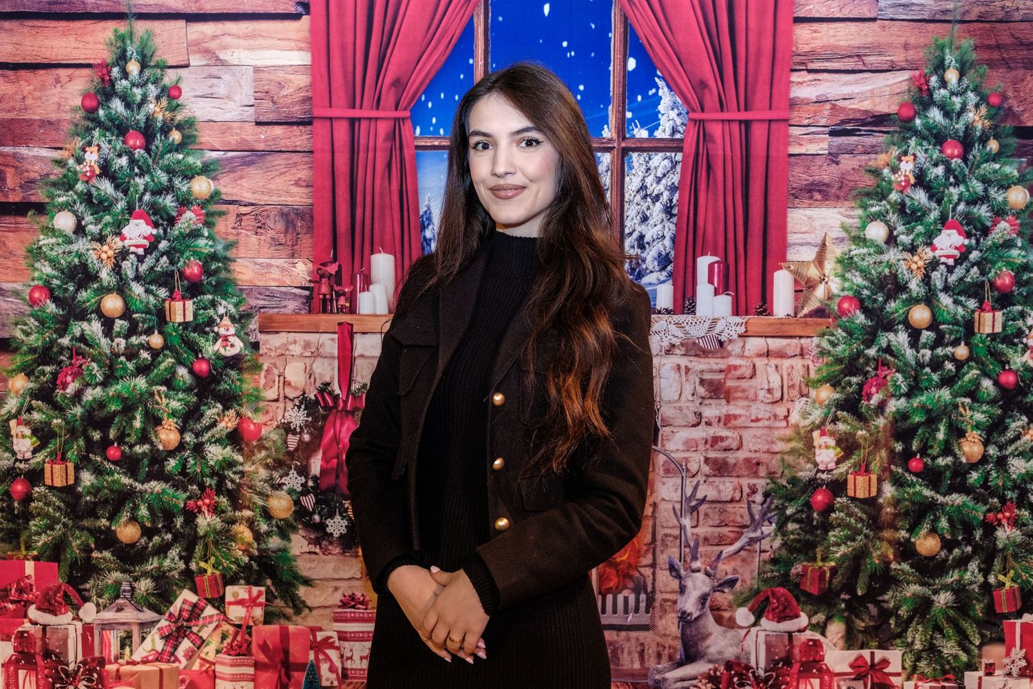 A festive Christmas scene with decorated trees, red curtains, and exposed brick wall in a cozy indoor setting.
