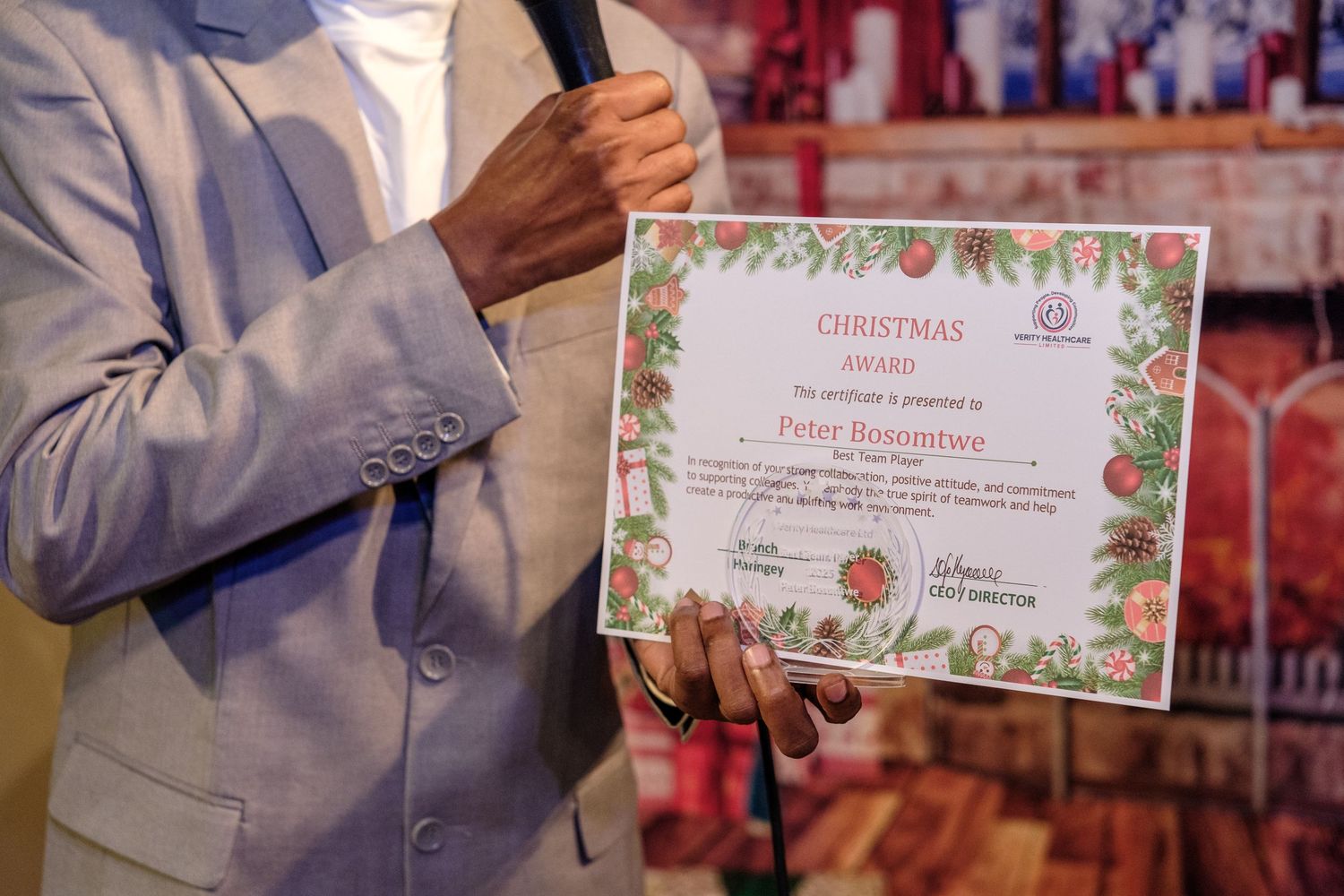Close-up view of hands holding a floral-decorated certificate award during a formal presentation ceremony.