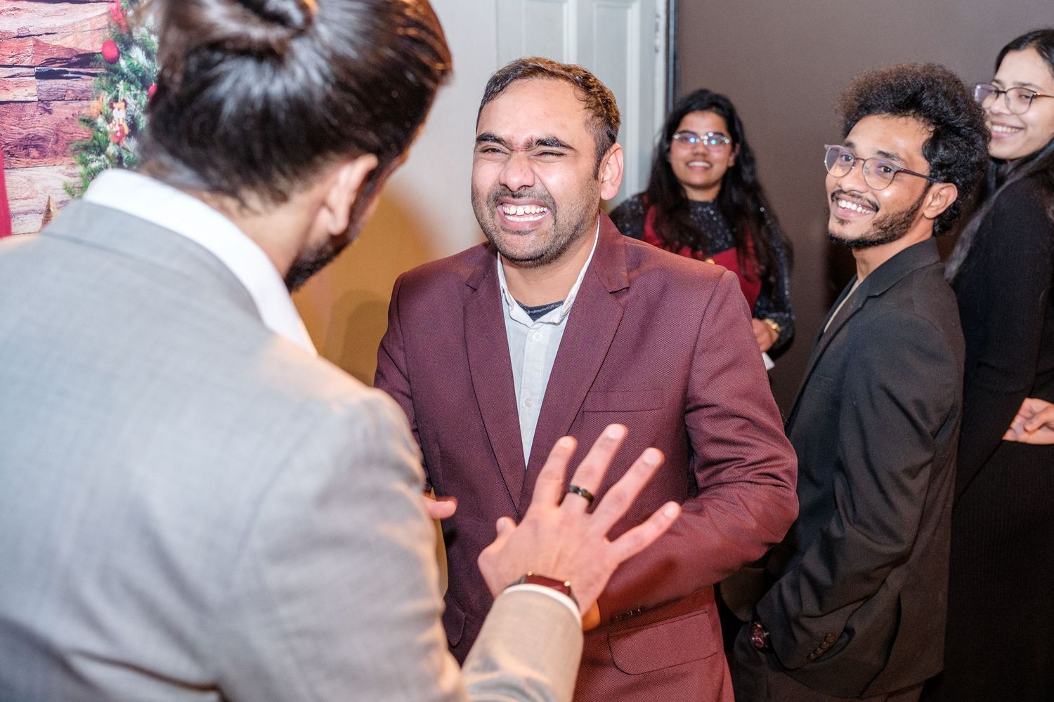 A group of people share laughter and conversation at a social gathering in a well-lit indoor space.