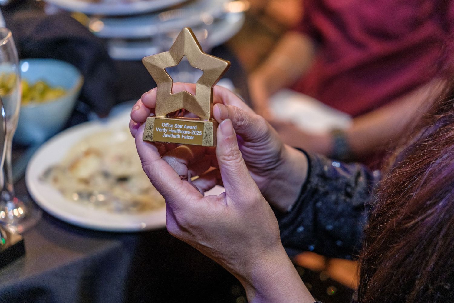 Close-up of hands holding a small golden star-shaped trophy or award during a celebration.