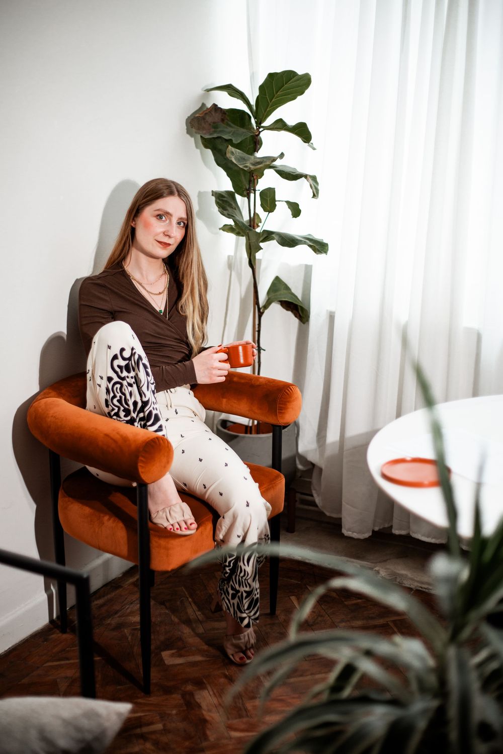Woman relaxing in orange velvet chair with coffee in modern interior. Hypnotherapy at Huddle Studio Plymouth