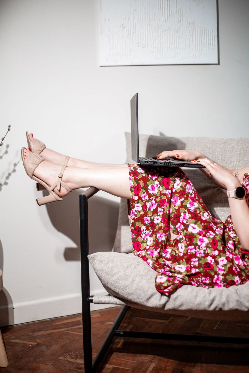 Legs in pink heels resting on chair wearing floral dress while using laptop.Hypnotherapy at Huddle Studio Plymouth