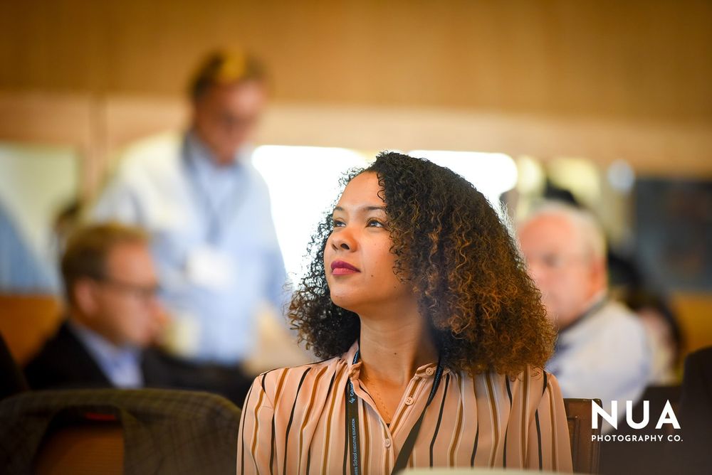 Attendees participate in a professional conference or business meeting in a warm-lit venue.