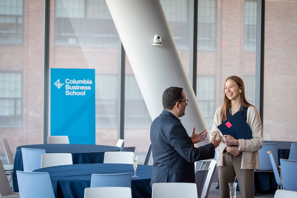 Business professionals collaborate in a modern office setting with glass walls and bright lighting.